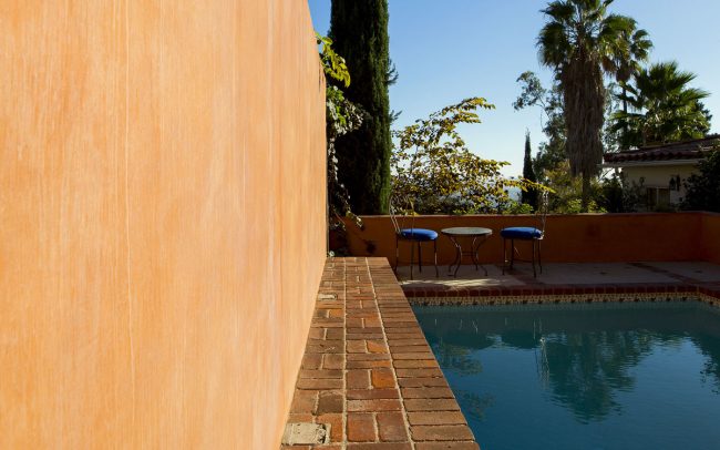 Pool with brick border and stucco wall